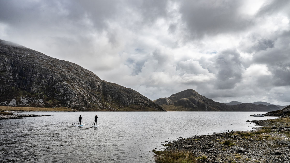 Wide shot of a loch with people paddleboarding